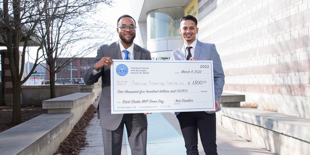 Dr. Cleamon Morer & Samer Alfahad smile and hold a large check for their $1,500 prize.