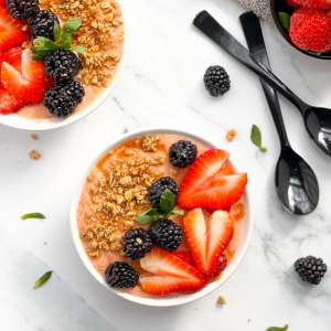 Two smoothie bowls with fruit and spoons 