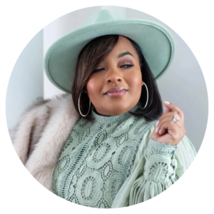 Shay Bailey, posing for a headshot wearing an aquamarine color shirt and hat with a fur coat for her business, My Beauty Kit