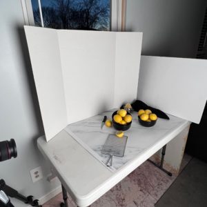 White bounce board used to deflect light onto lemons during food photography photoshoot 