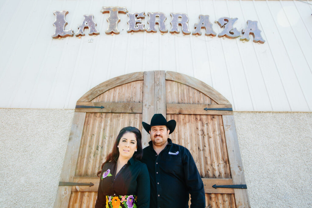 A woman and man smile and stand outside of their restaurant, La Terraza