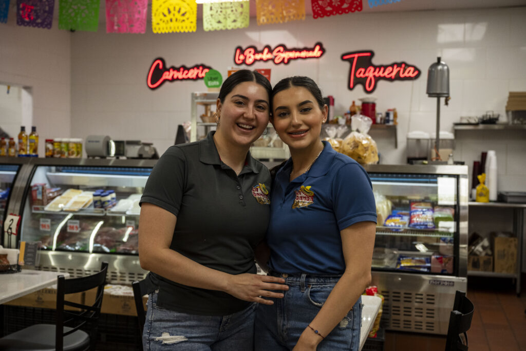 Jennifer and Chantel Garcia smile standing inside of their family business, The Bamba Supermarket