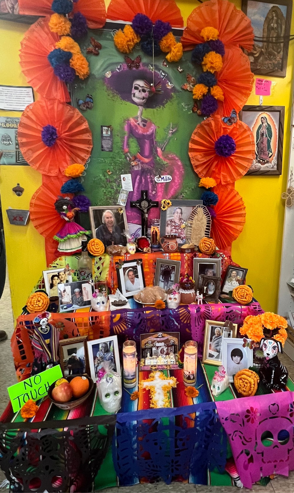 A display of ofrenda at El Popo Market. The display includes flowers. framed photos and candles