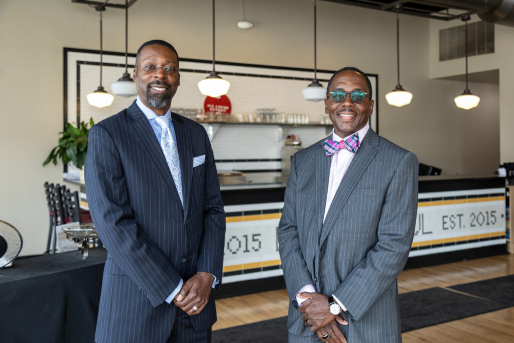 Two men wearing suits smile for a photograph inside their restaurant, Detroit Soul