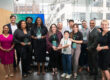 A group of people smiling for a photograph. Several of them are holding up Salute Award trophies from TechTown Detroit