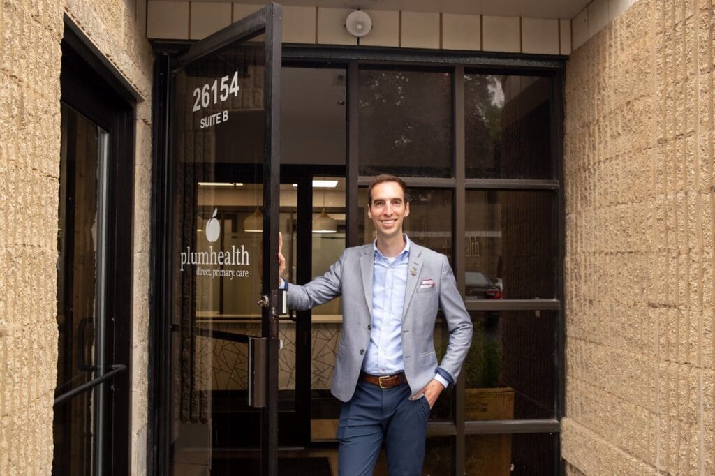 A photo of Dr. Thomas standing outside the front door of the Plum Health location in Corktown Detroit. 