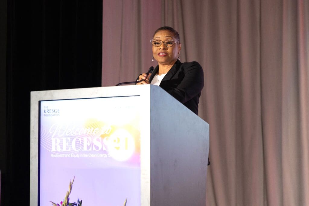 Carla Walker-Miller stands on a stage, speaking into a microphone on a podium