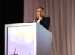 Carla Walker-Miller stands on a stage, speaking into a microphone on a podium