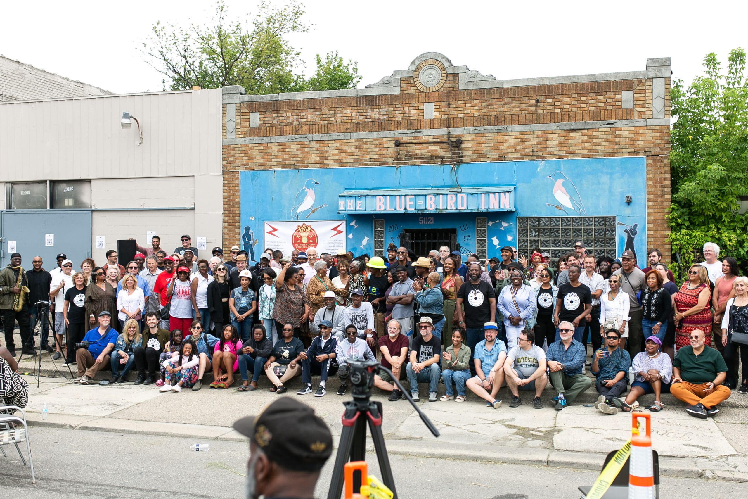 A diverse group of people gathering in front of The Bluebird Inn, a historical music venue.