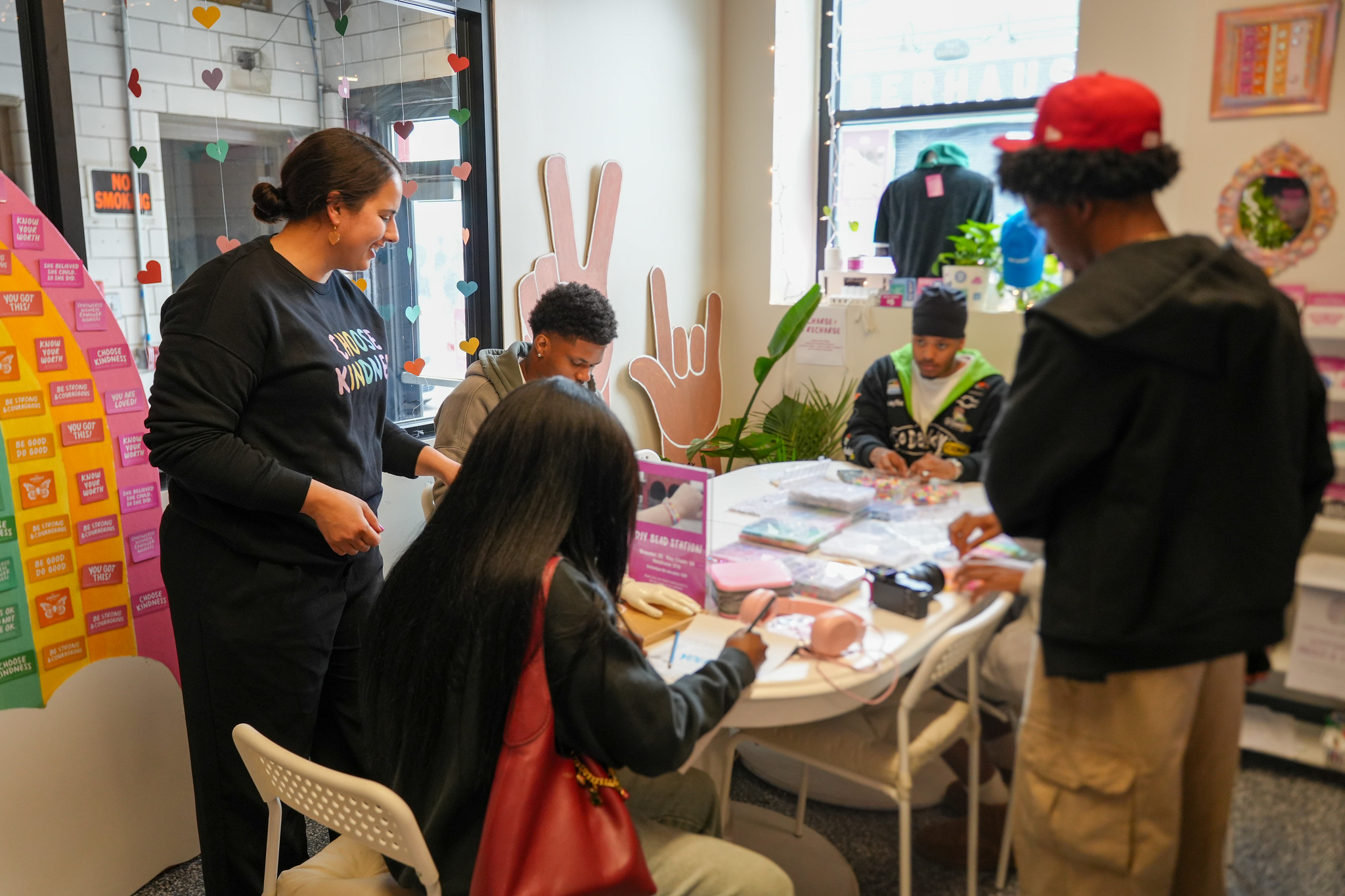 A group of students working togther at a table to prepare crafts fro an upcoming event.