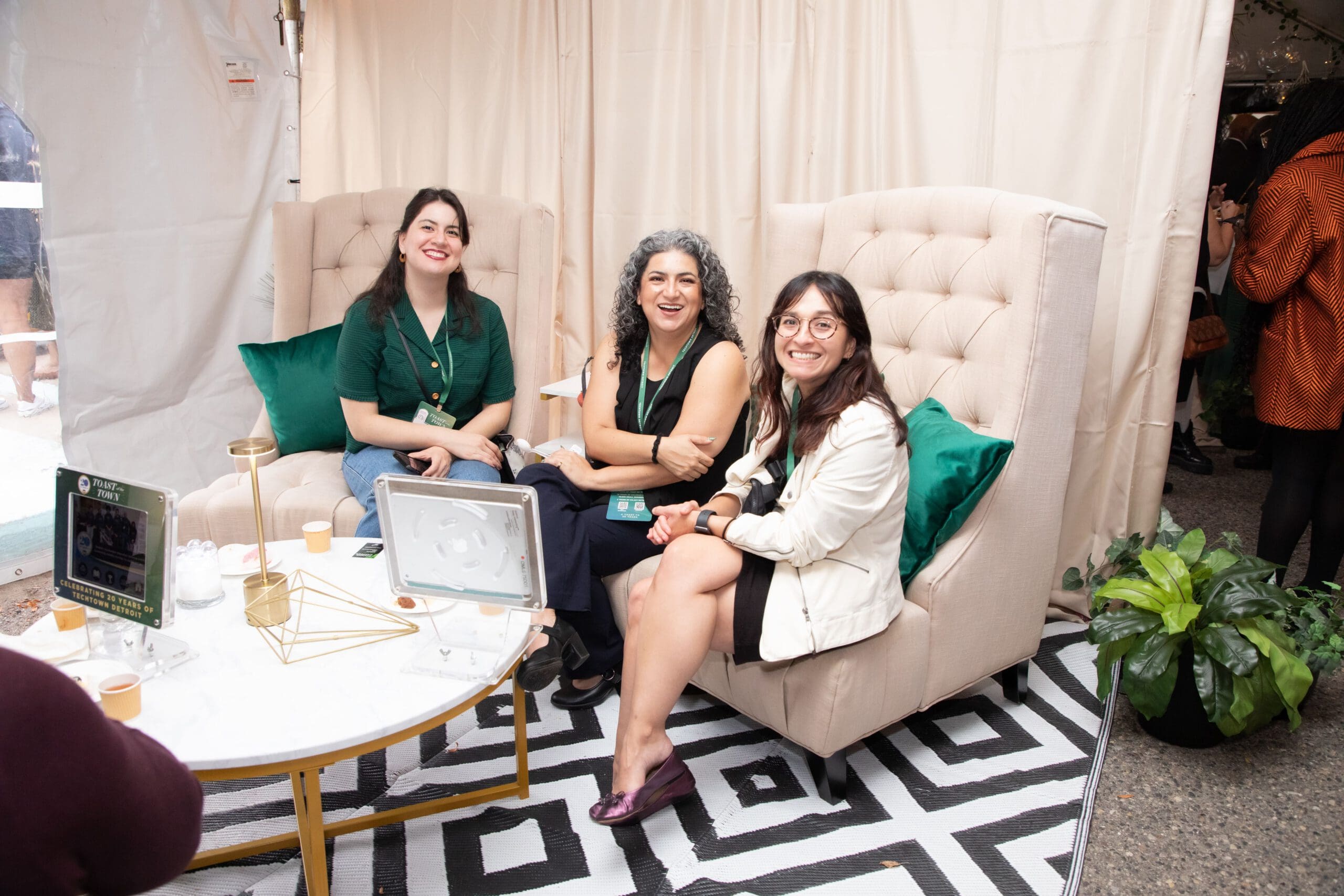 Three people sitting on chairs and smiling for a photograph