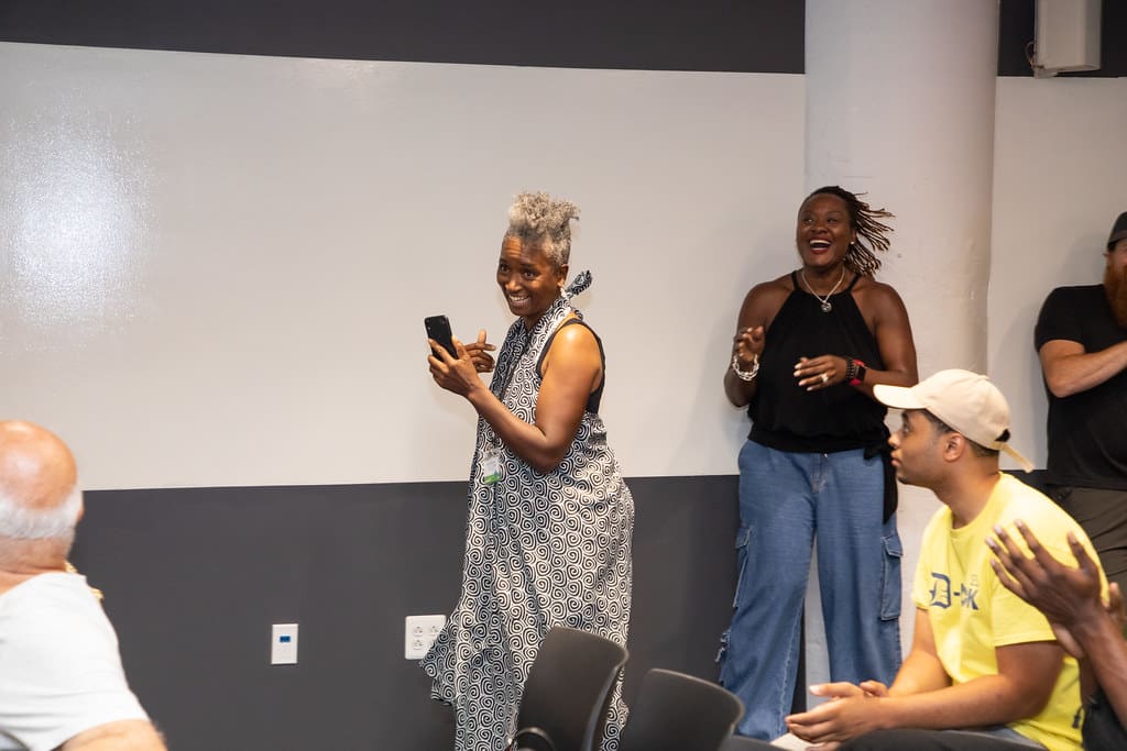 A woman smiles while walking and holding up a phone