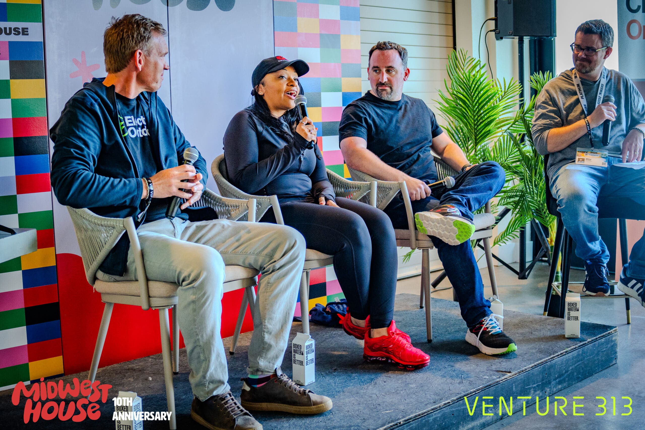 Four people seated in a row of chairs on a stage, each of them holding microphones. Overlapping this photo are the logos for Midwest House and Venture 313