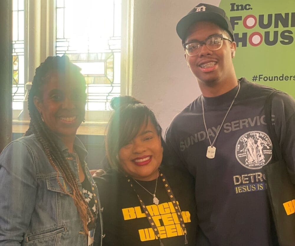 Two women and one man stand next to each other and smile for a photograph.