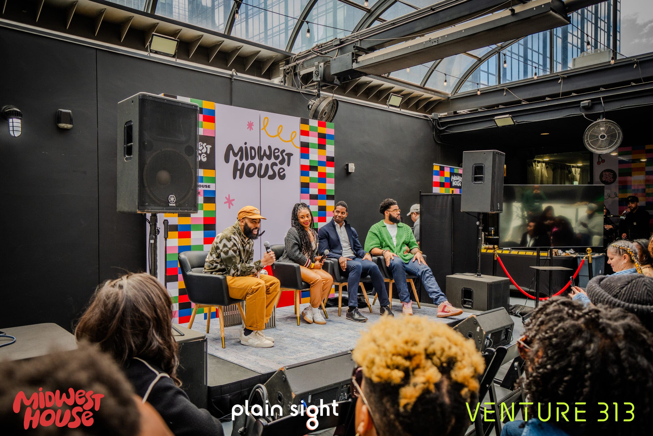 Four people sit in a line of chairs on a stage, speaking to a group of people seated in an audience. Behind the people on stage is signage for the organization Midwest House. Overlapping the photo are images of the logos for Midwest House, Plain Sight and Venture 313