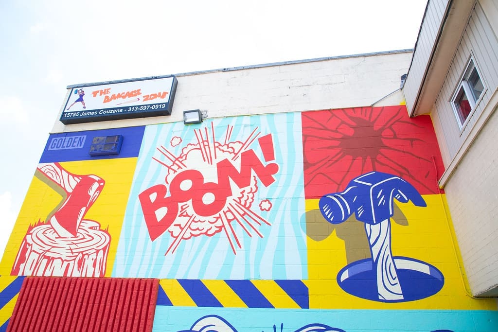 An exterior wall of Detroit-based rage room, The Damage Zone, featuring illustrations of axes and the word "Boom!"
